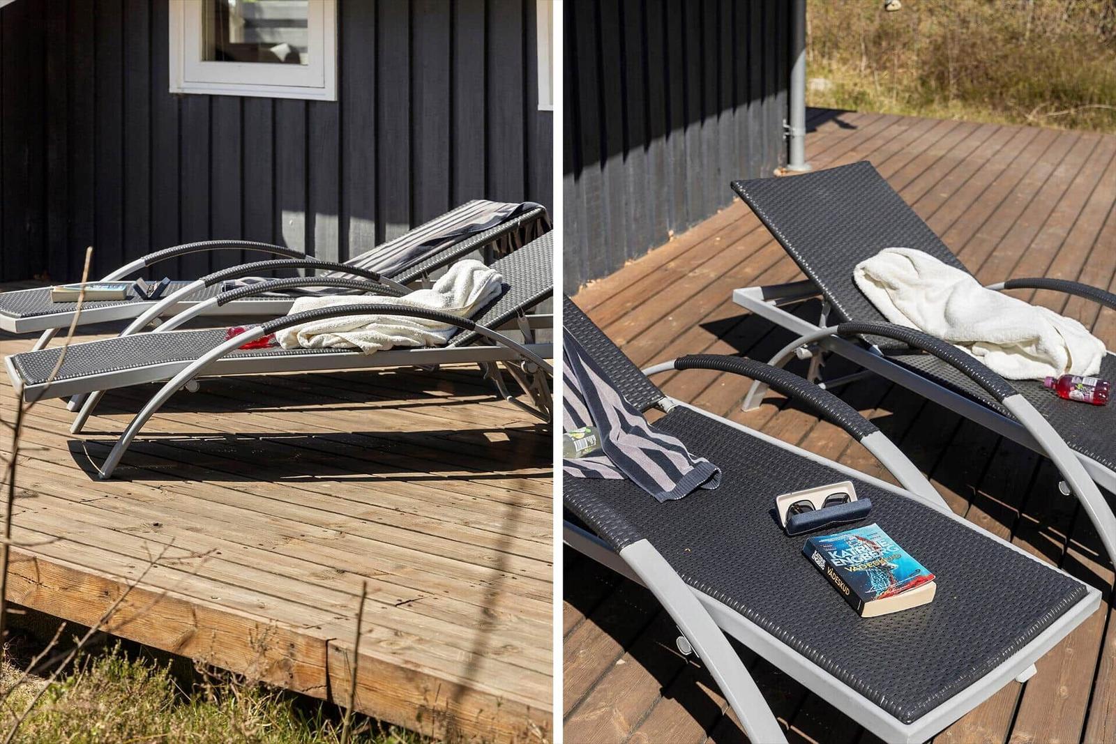 Two lounge chairs on a wooden deck in front of a house with a window.