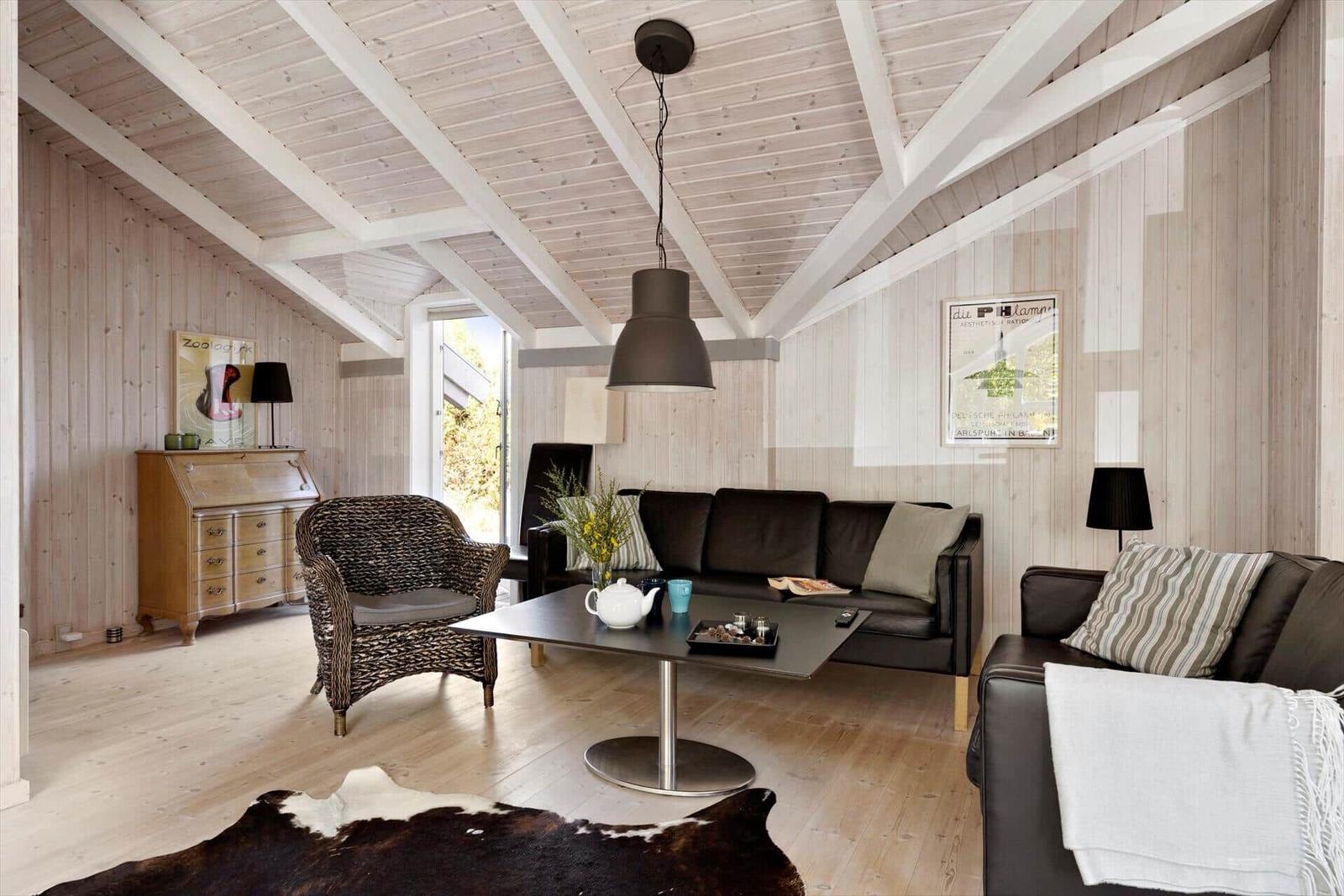 Living room with wooden walls, sofa, armchair, and table.