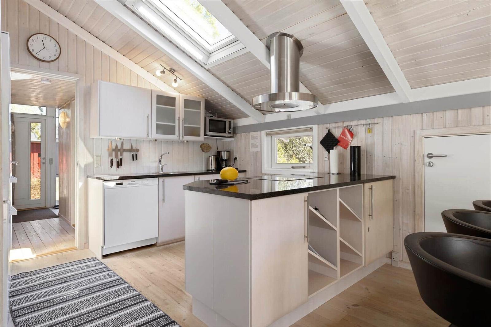 Kitchen with island, white cabinets, and wooden ceiling with skylight.