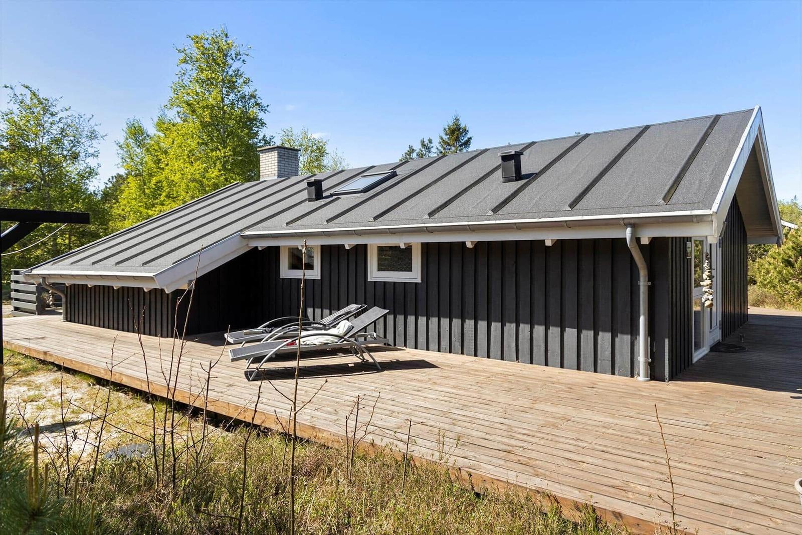 Modern wooden cabin with terrace and loungers in the woods