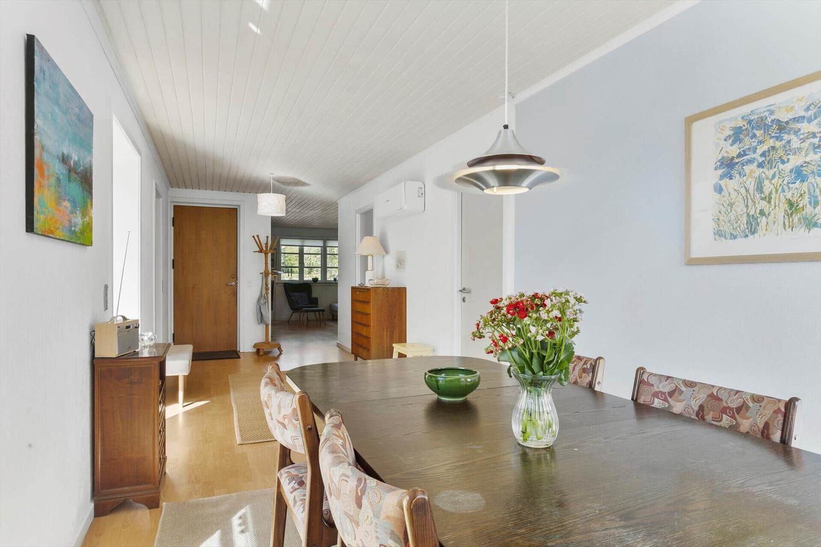 Esszimmer mit Holztisch, Stühlen und Blumen. An der Wand hängen Bilder.