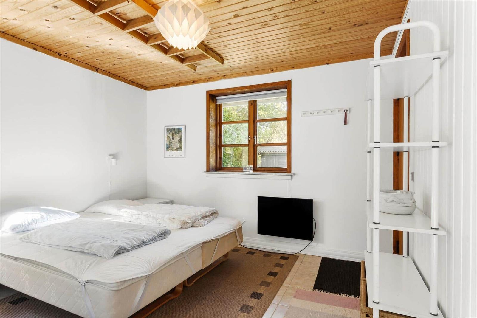 Schlafzimmer mit Bett, Fenster und Regal.