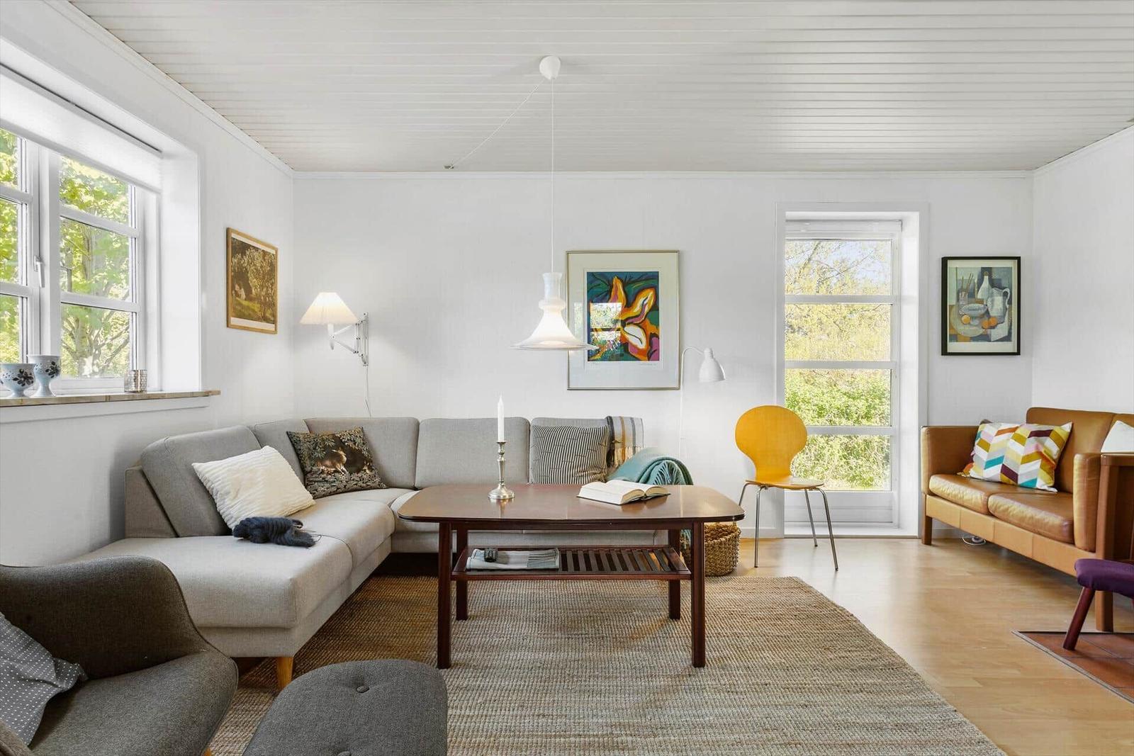 Wohnzimmer mit grauem Sofa, Holztisch und gelber Stuhl