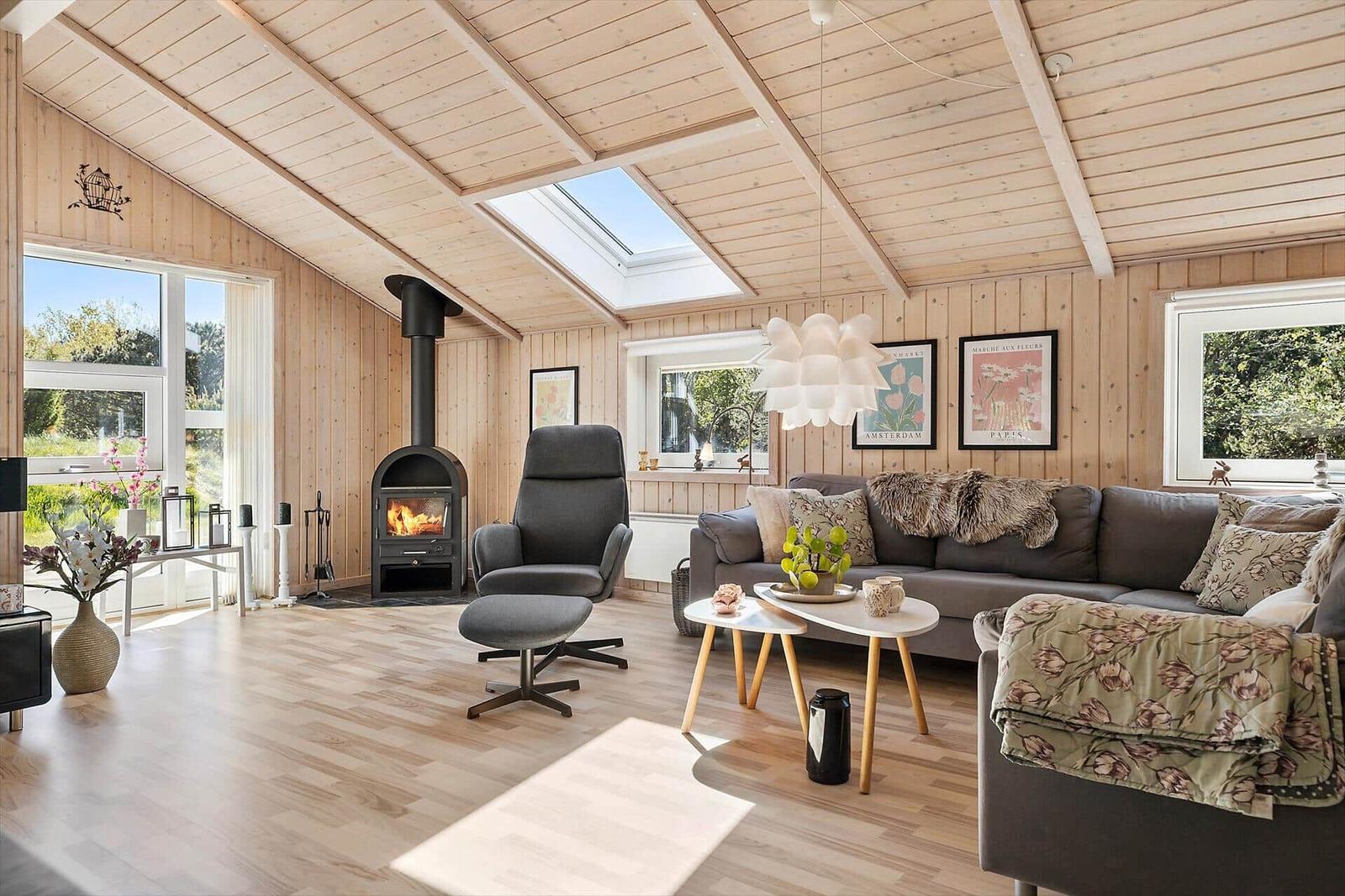 Wohnzimmer mit Holzwand, Kamin, Sofa und Fenstern.
