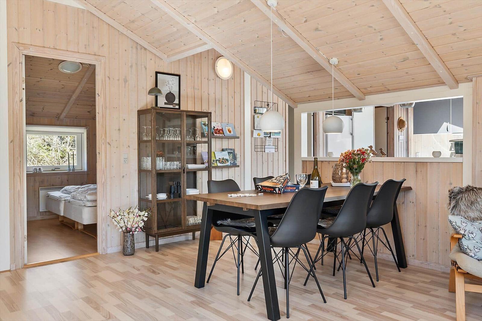 Esszimmer mit Tisch, Stühlen und Glasvitrine. Durchgang zu Schlafzimmer mit Bett.