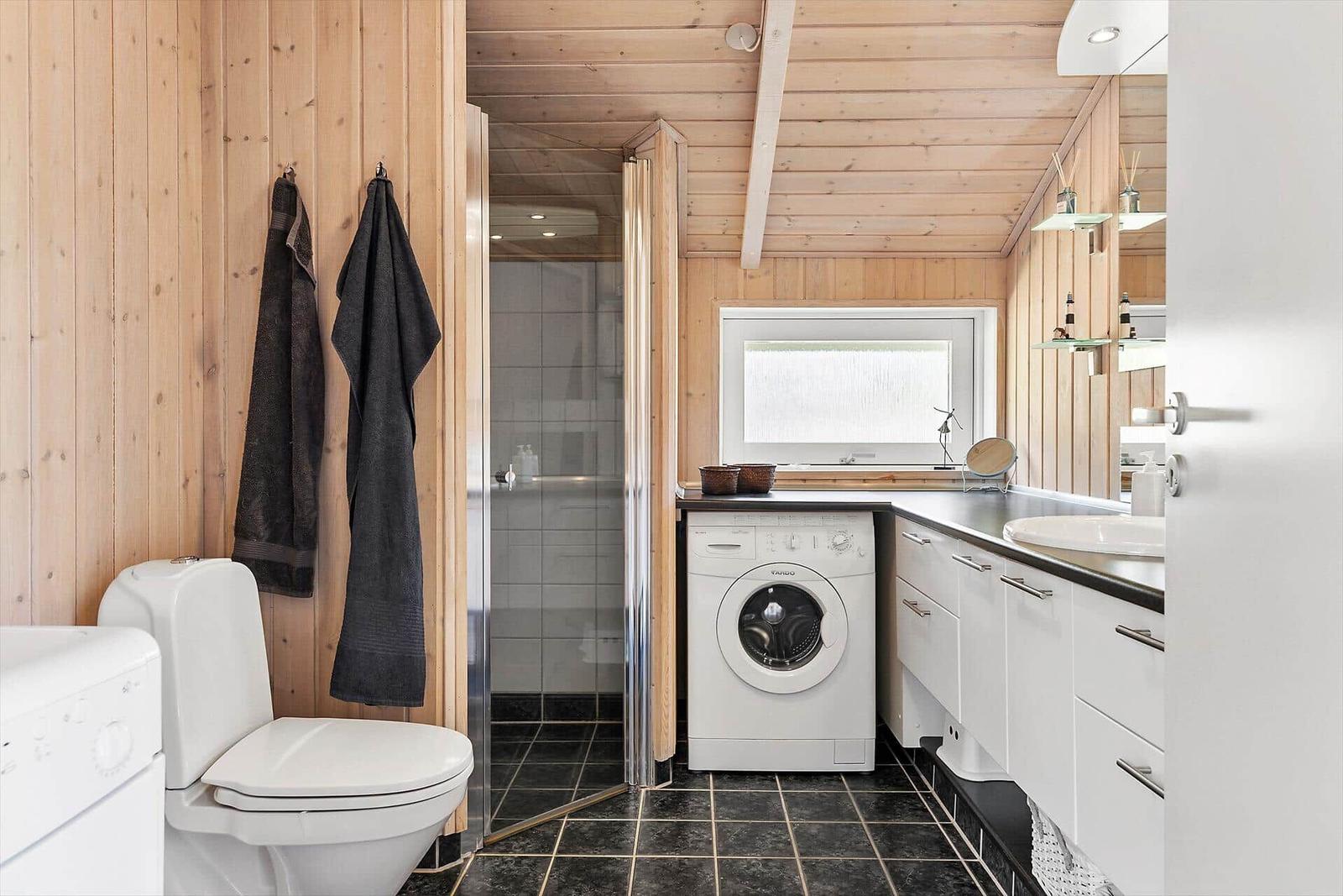 Badezimmer mit Toilette, Waschmaschine und Dusche.