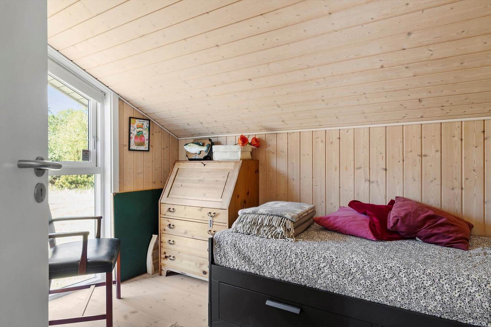 Bedroom with bed, desk, and window.