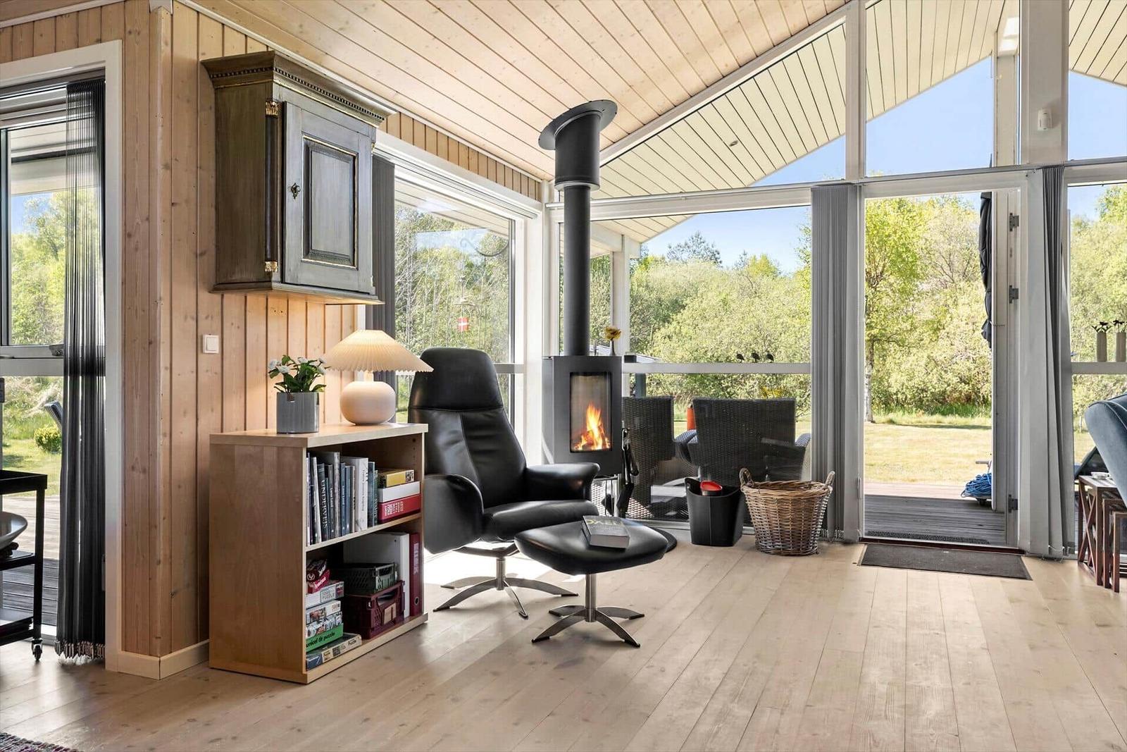 Living room with wooden ceiling, fireplace, and large window view of the garden.