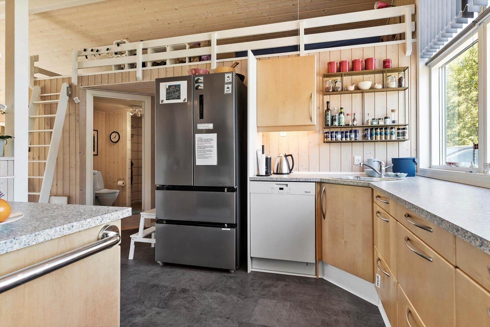 Kitchen with fridge, sink and wooden cabinets. Upper level with sleeping area.