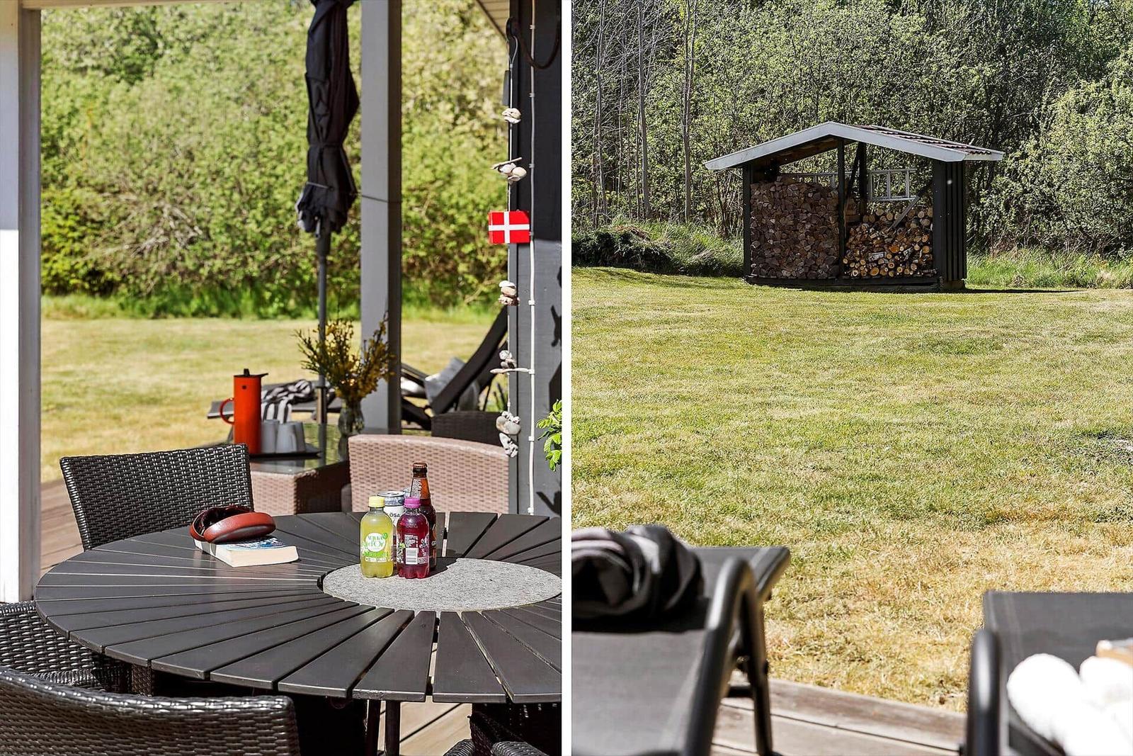 Terrace with table and chairs, next to woodpile in the garden.