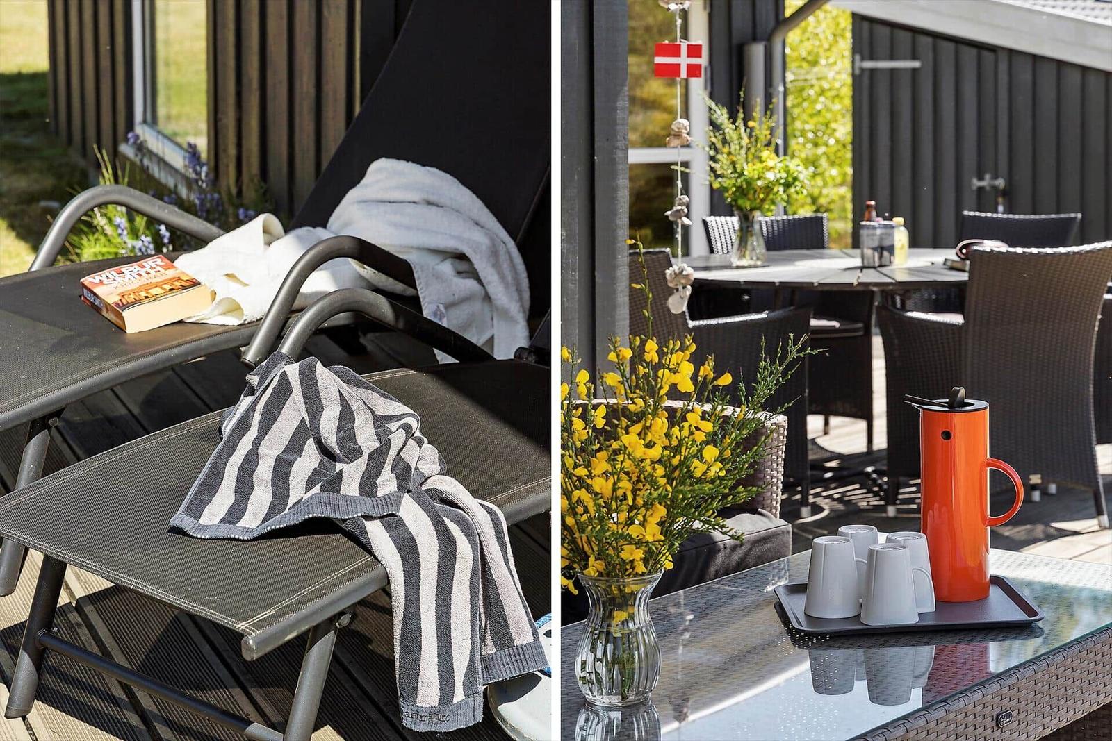 Terrace with loungers, table, and flowers. Beside it stands an orange thermos pot.