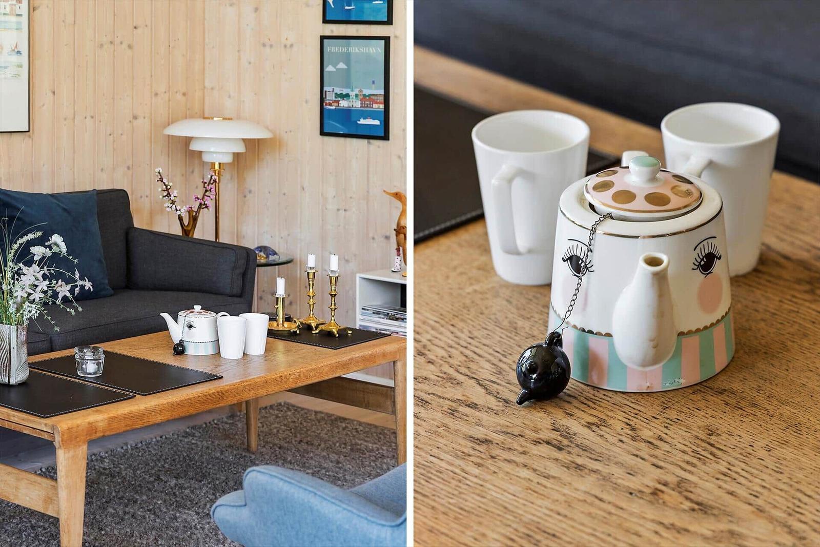 Living room with wooden wall, sofa, and table with teapot. Detail: teapot with eyes on table.