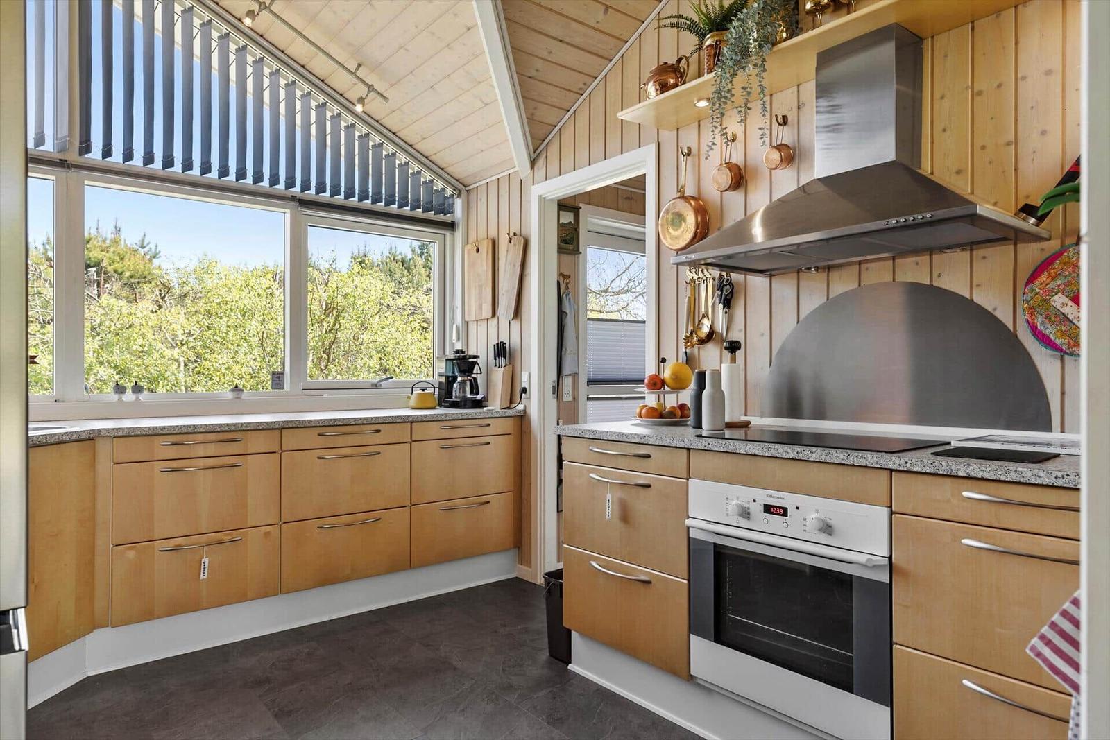 Kitchen with wood paneling, windows, stove, and oven.