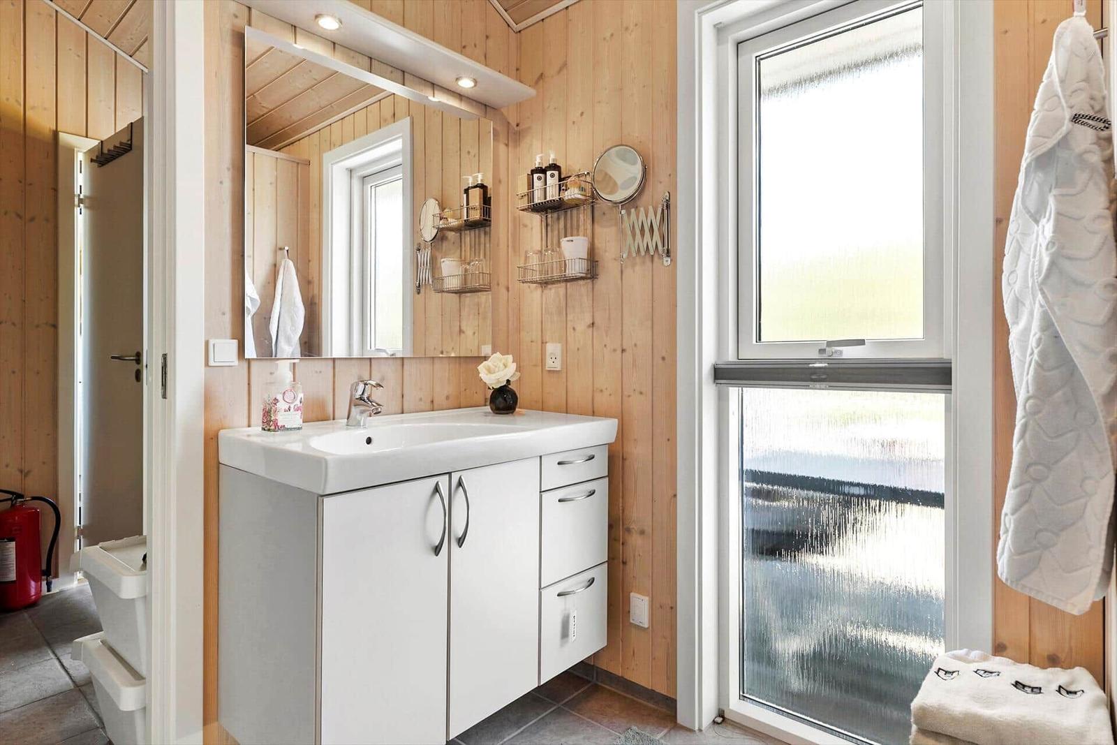 Bathroom with wooden walls, sink, and window
