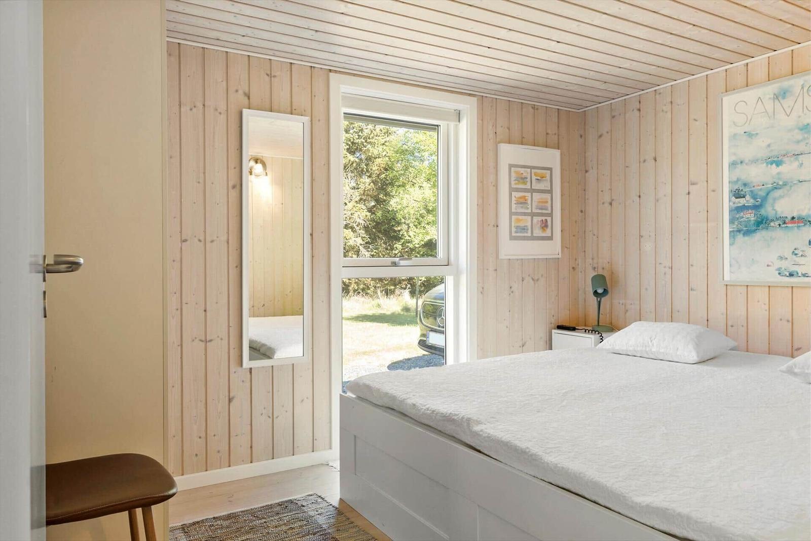 Bedroom with wooden walls, window, and bed