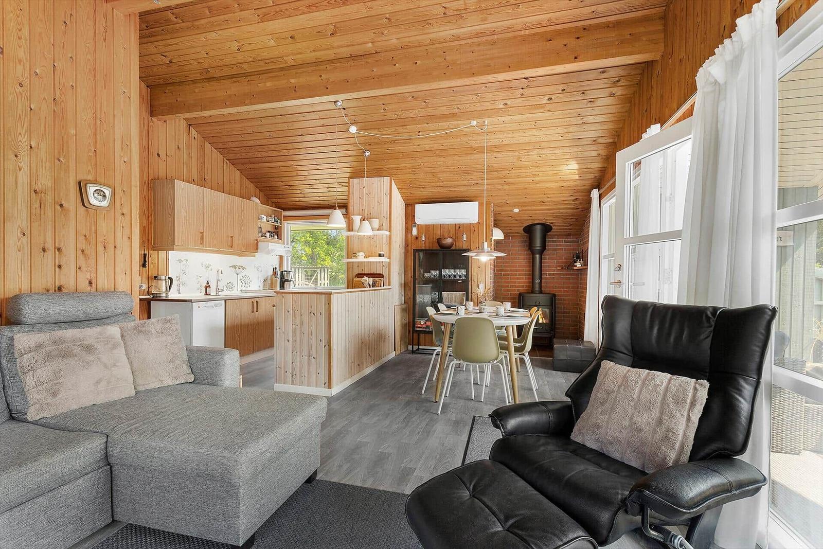 Living and dining area with wooden walls, sofa, and dining table.