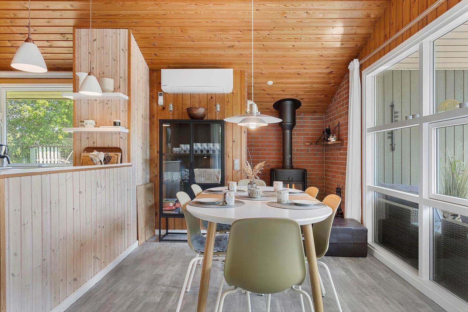 Dining area with round table and chairs, wooden walls and fireplace