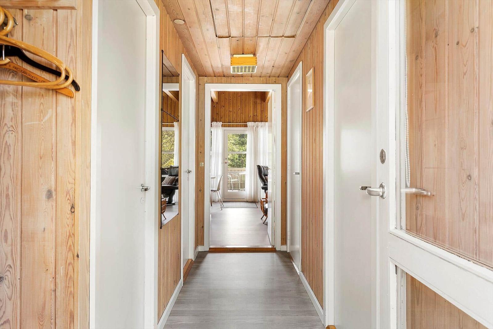 Hallway with wooden walls and doors to various rooms.