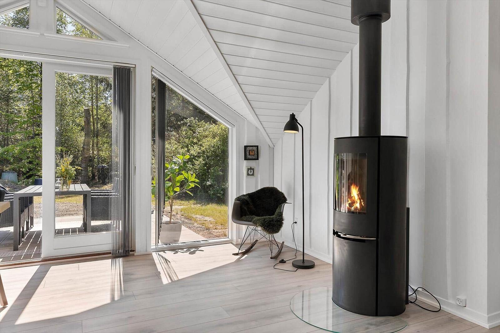 Raum mit Kamin, Sitzgelegenheit und großem Fenster zur Terrasse.