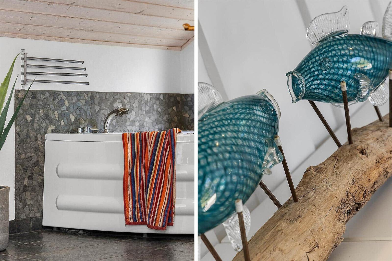 Bad mit Badewanne, Mosaikwand und Glasfischen auf Holzstamm