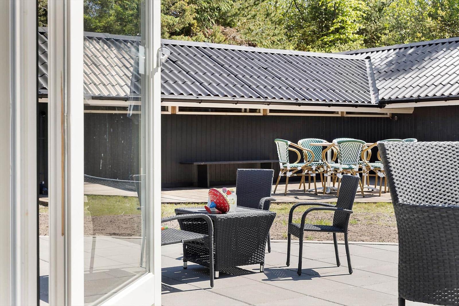 Terrasse mit Sitzgruppe und Blick auf Gartenbereich mit Tisch und Stühlen.