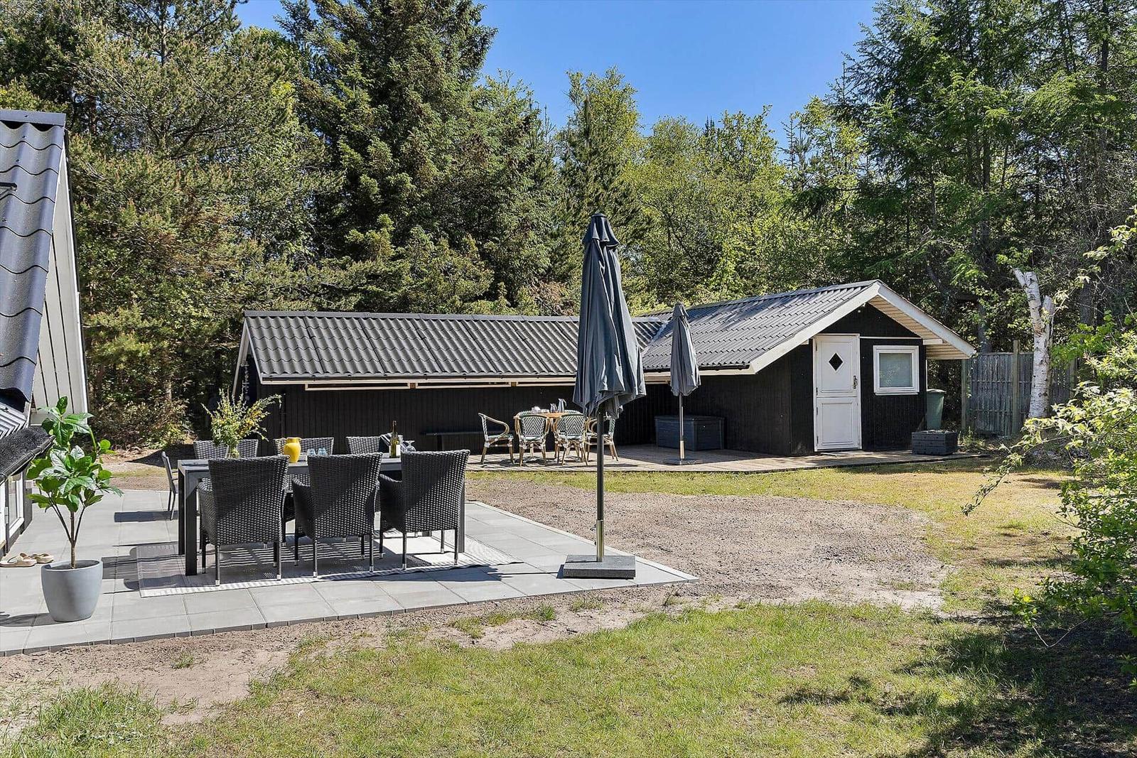 Haus mit Terrasse, Garten und Außensitzgelegenheiten.