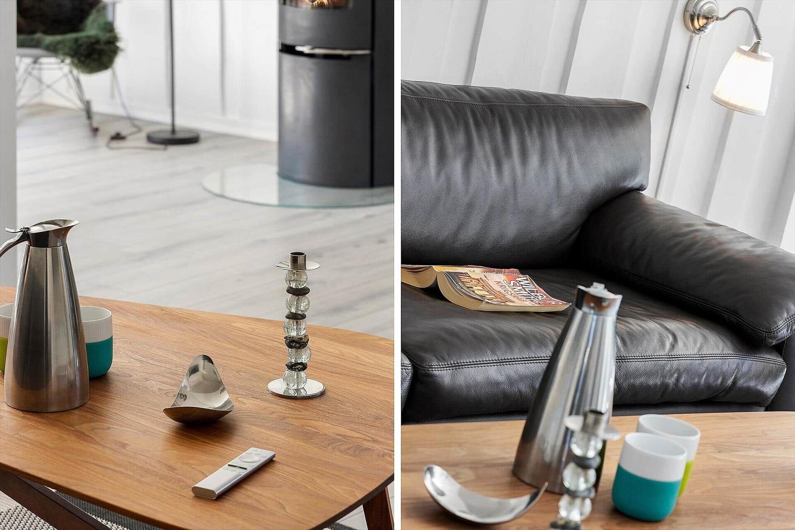 Holztisch mit Kanne, Tassen und Fernbedienung vor Sofa und Kamin