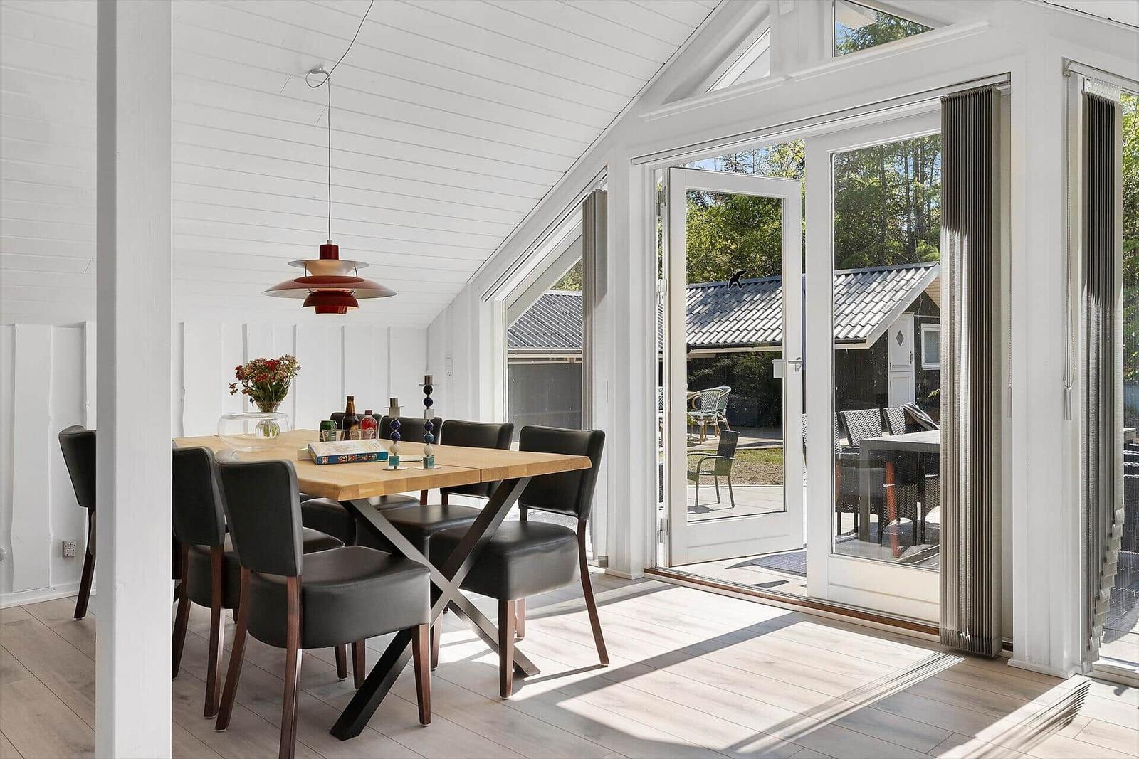 Esszimmer mit Holztisch, schwarzen Stühlen und Glasfront zur Terrasse.