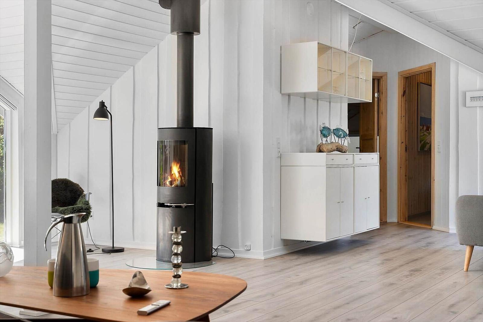 Moderne Wohnküche mit Kaminofen, Holzdielen und weißen Schränken.
