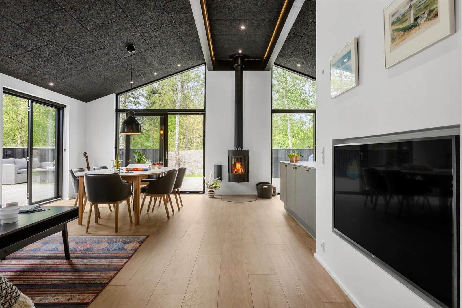 Modernes Wohn- und Esszimmer mit Holzboden, Kamin und großen Fenstern.