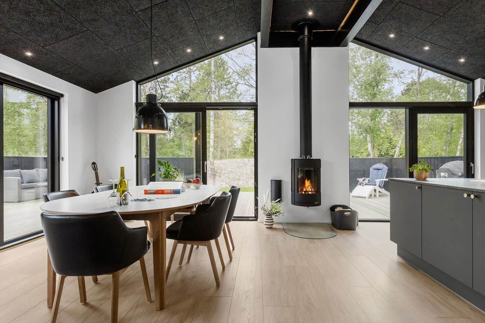 Moderne Küche mit Esstisch, Kamin und großzügigen Fenstern zum Garten.
