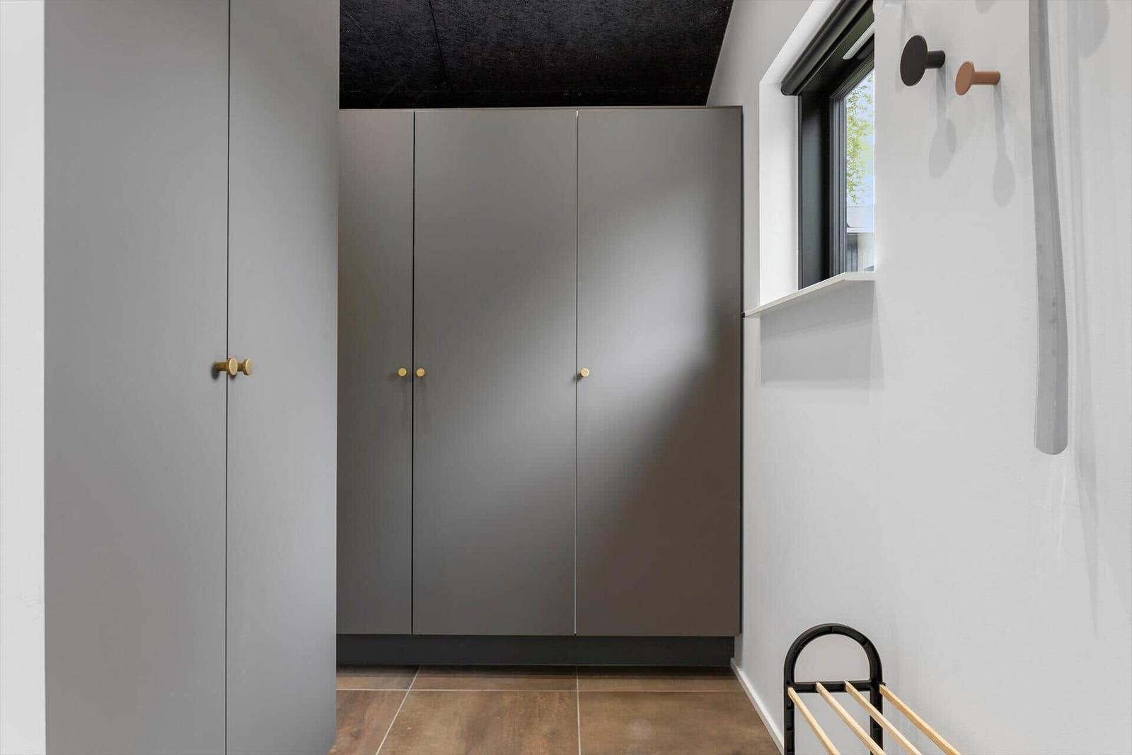 Schwarzer Kleiderschrank mit goldenen Griffen an der Wand