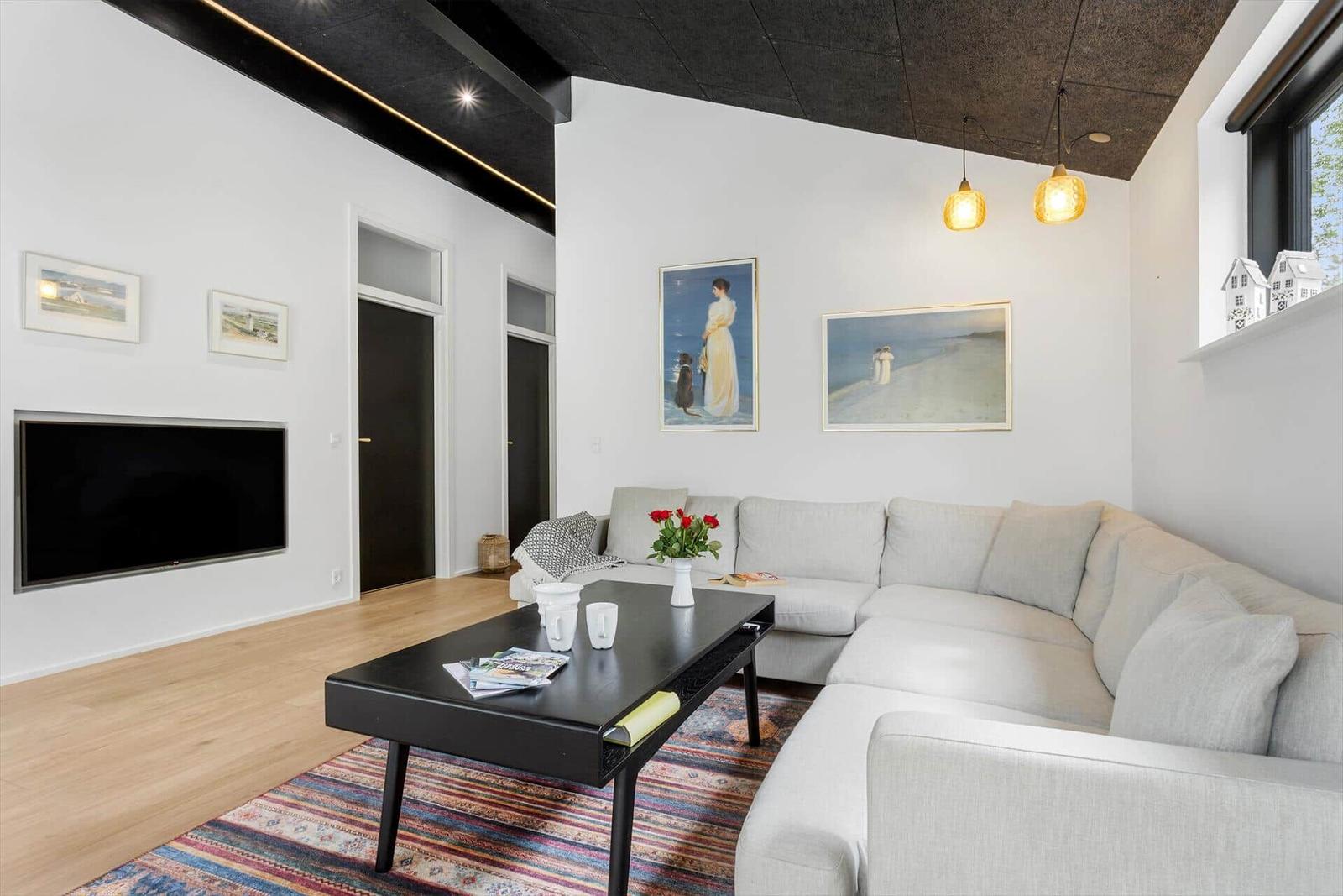 Wohnzimmer mit Sofa, Couchtisch und Fernseher an der Wand.