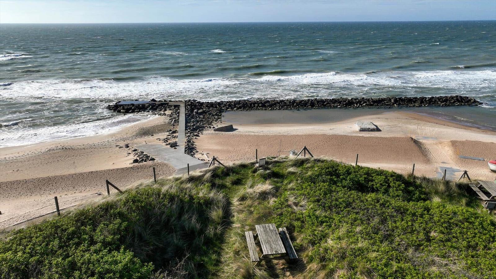 Strand mit Steinschutz und Picknicktisch auf Dünen