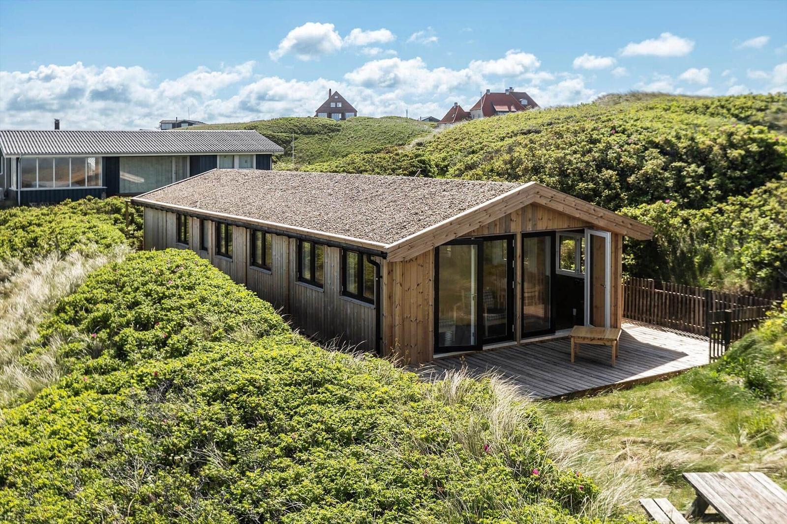 Holzhaus mit Terrasse und Aussicht auf grüne Hügel