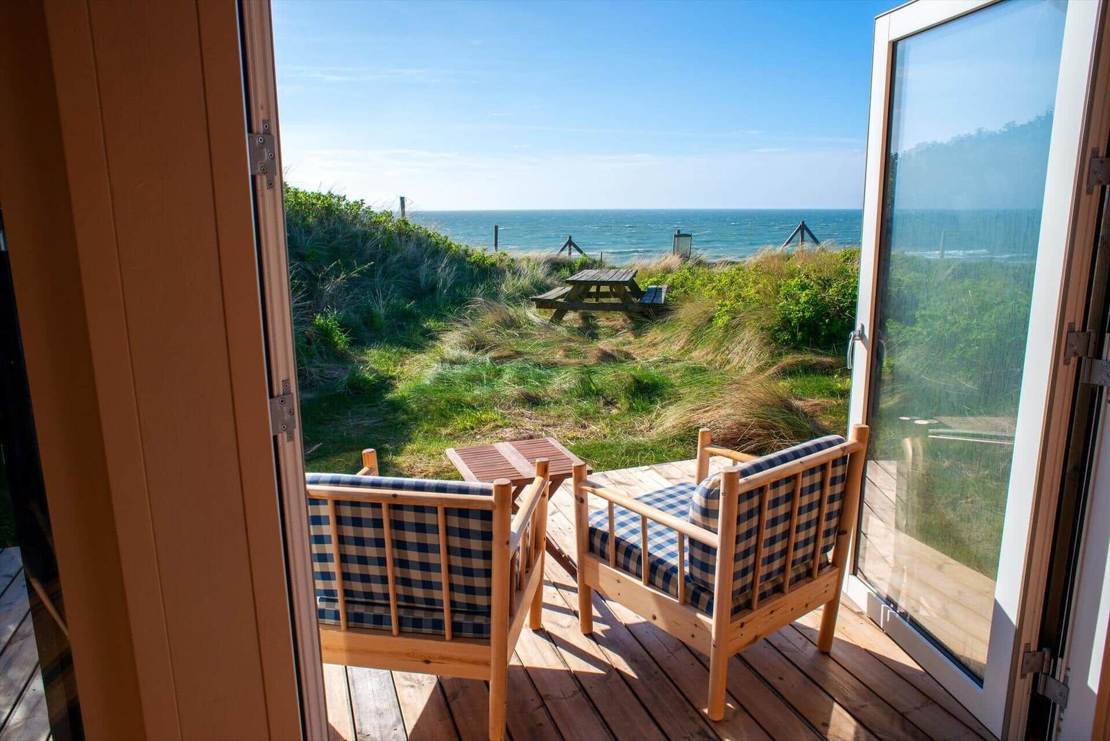 Terrasse mit zwei Stühlen und Blick auf Strand und Meer.