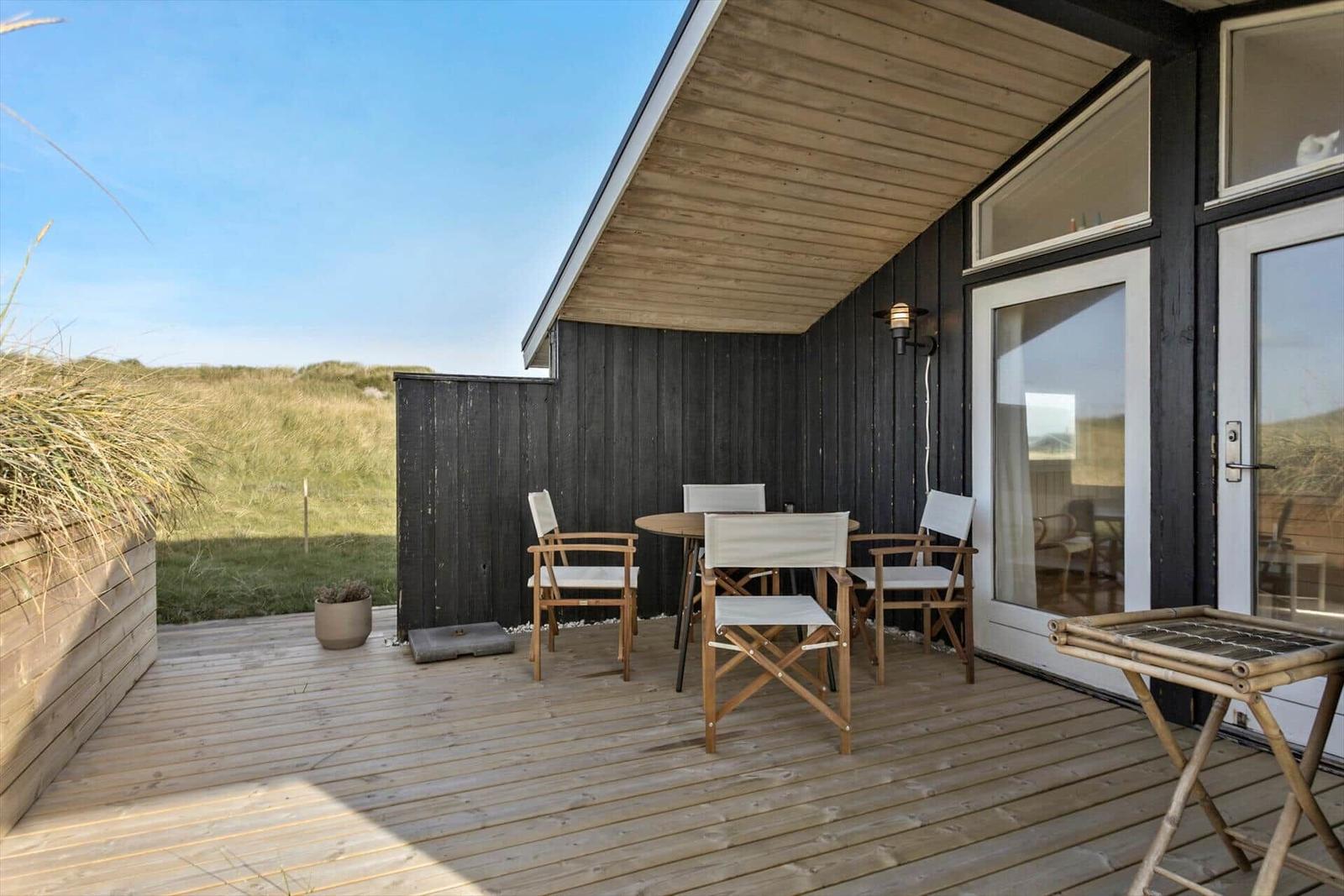 Deck with table, chairs, and grill area. View of dunes.