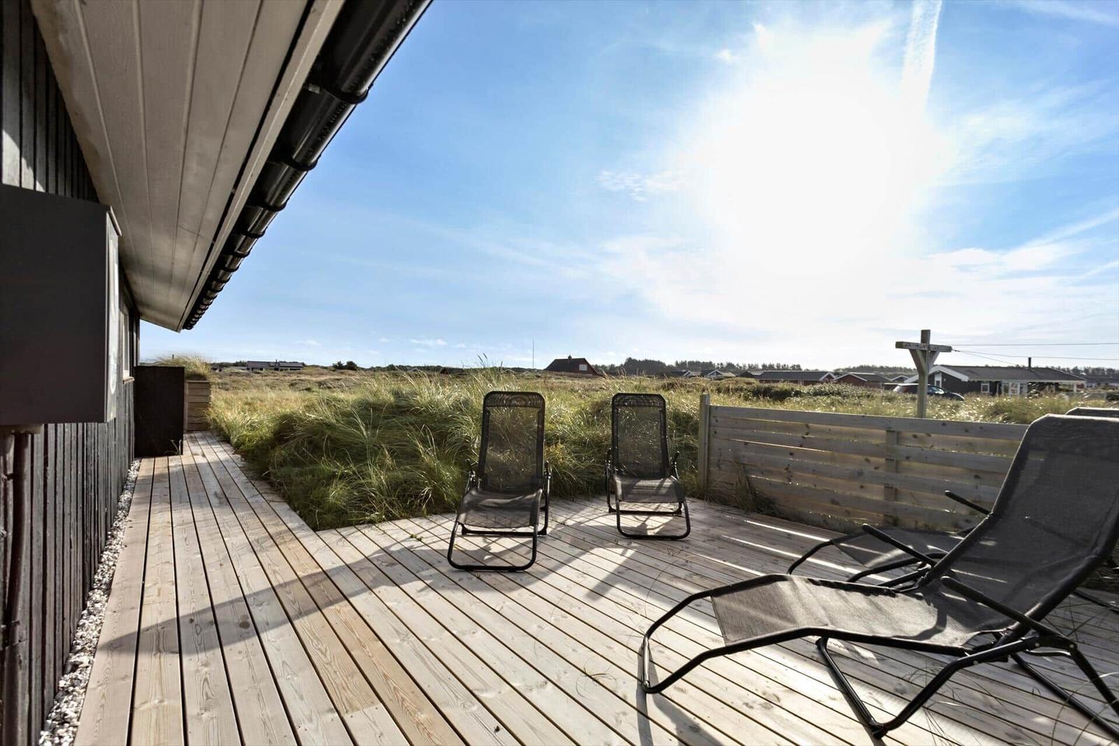 Deck with lounge chairs and view of grassland.