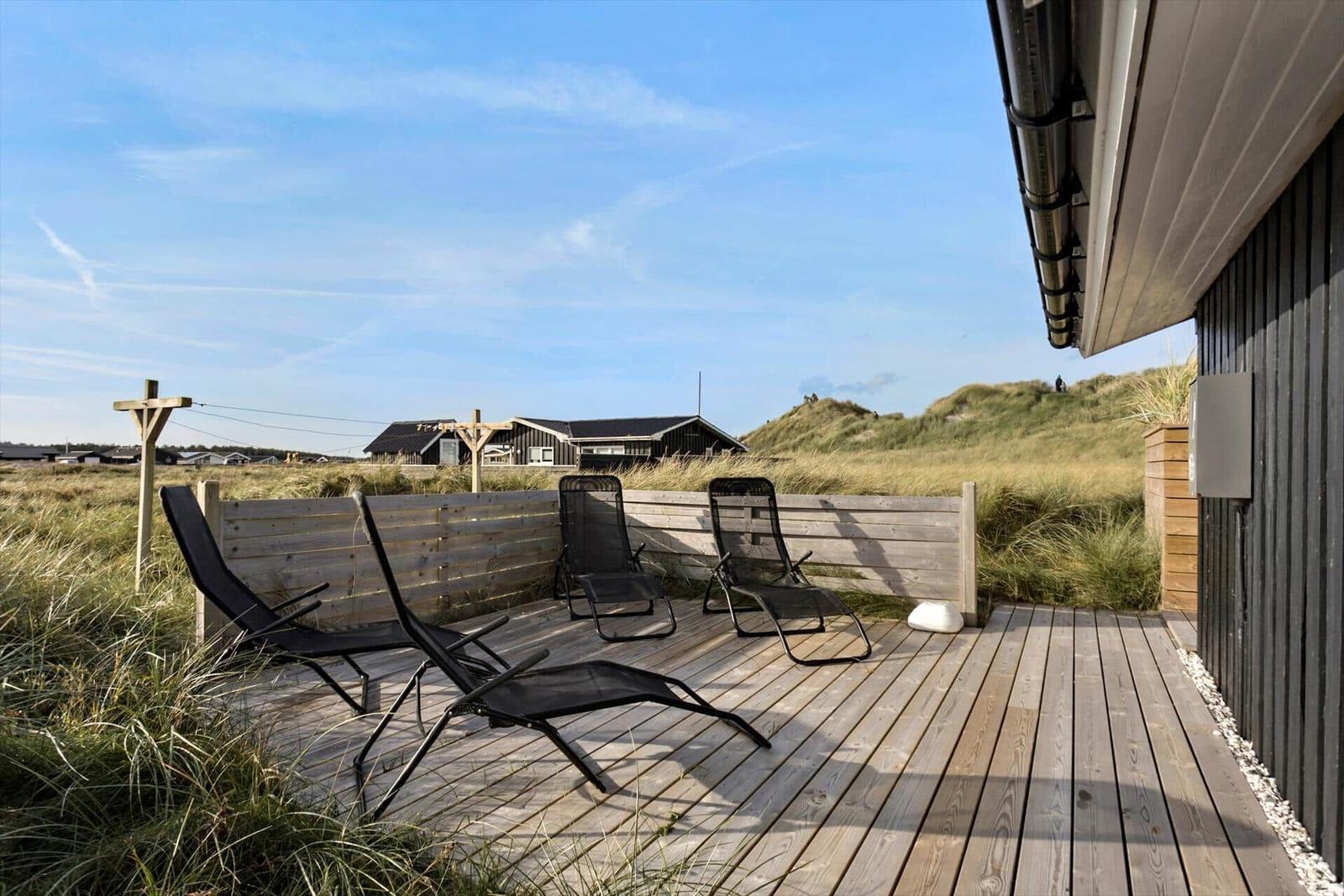 Deck with lounge chairs and view of dune landscape.