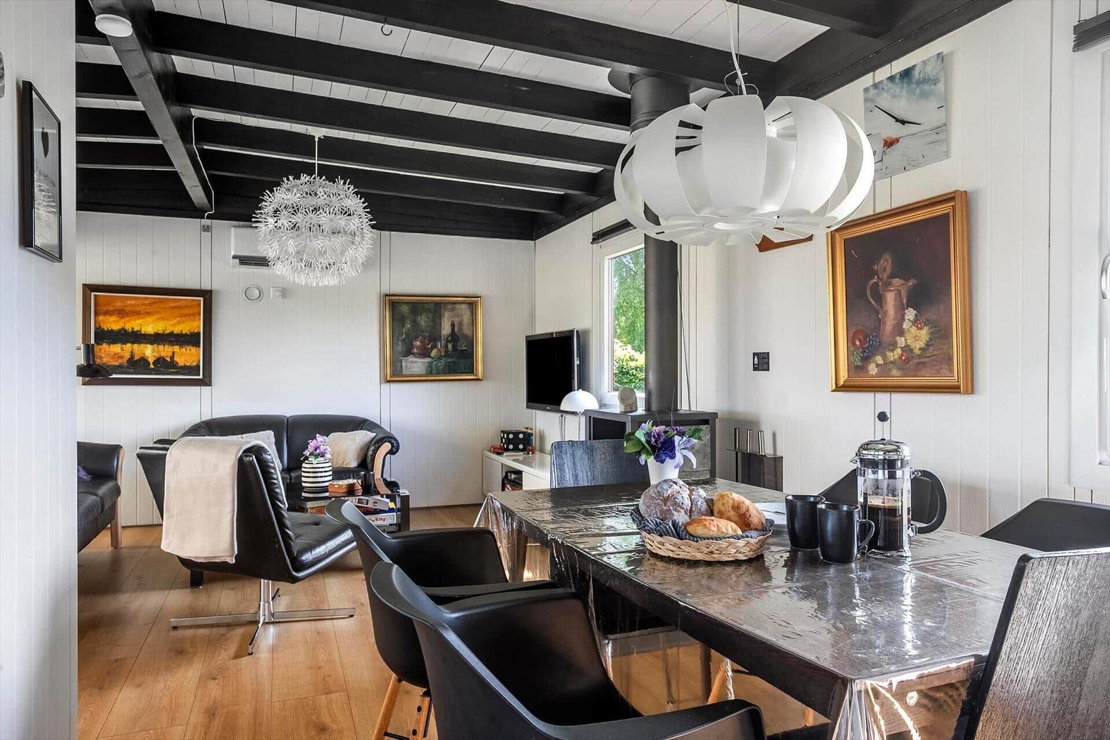 Dining area with table, chairs, and kitchenette. Living area with sofa and wall art.