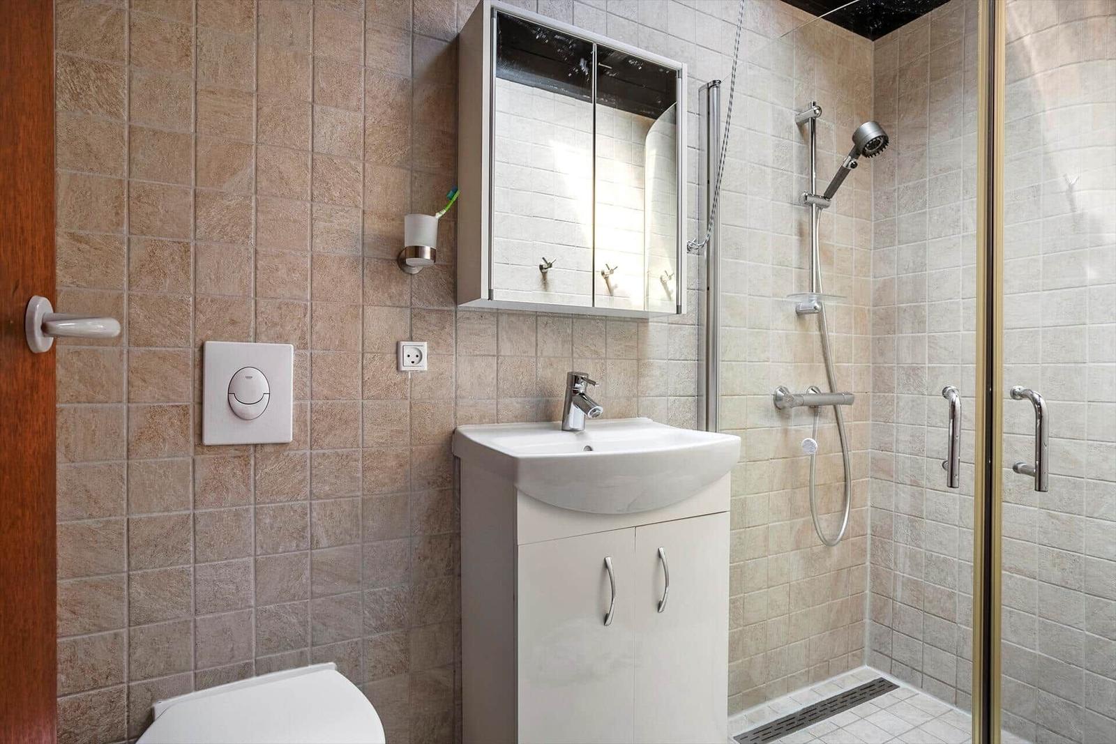 Bathroom with shower, sink, and mirror cabinet.
