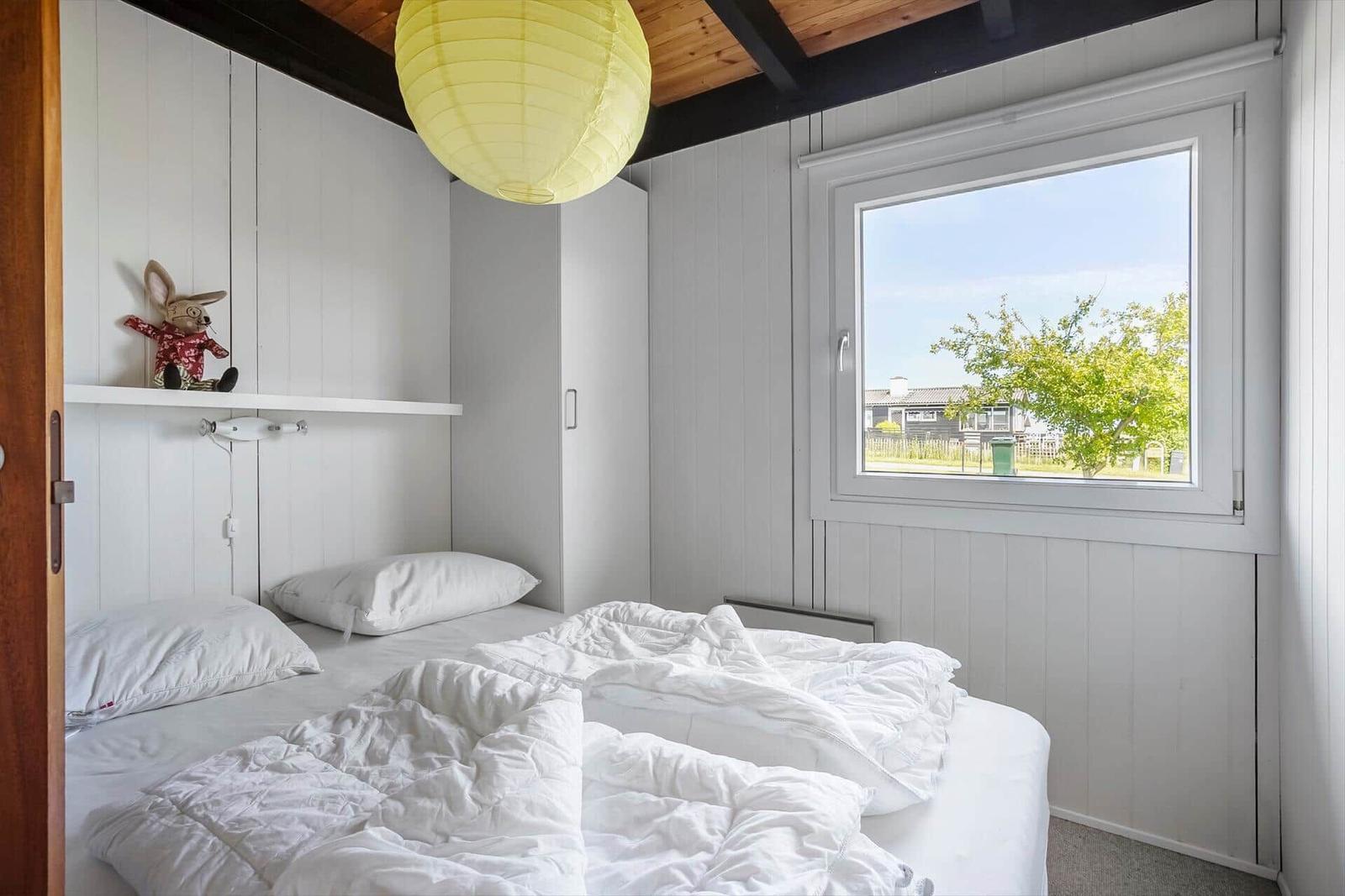 Bedroom with white bed, window, and yellow lantern.