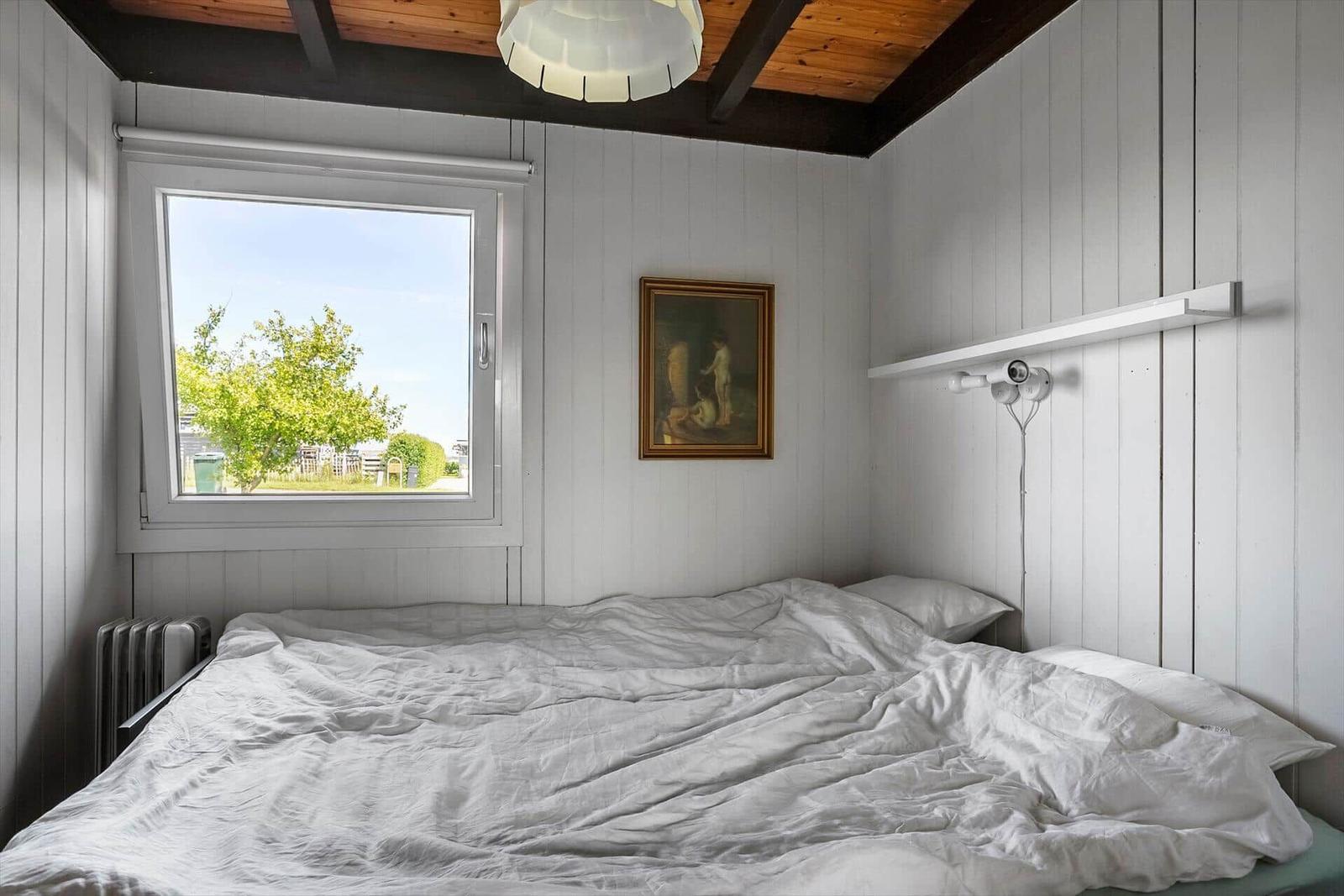 Bedroom with bed, window, and ceiling beams.