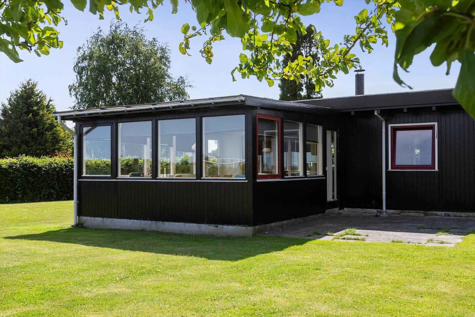 Black house with large window area and green lawn in front.