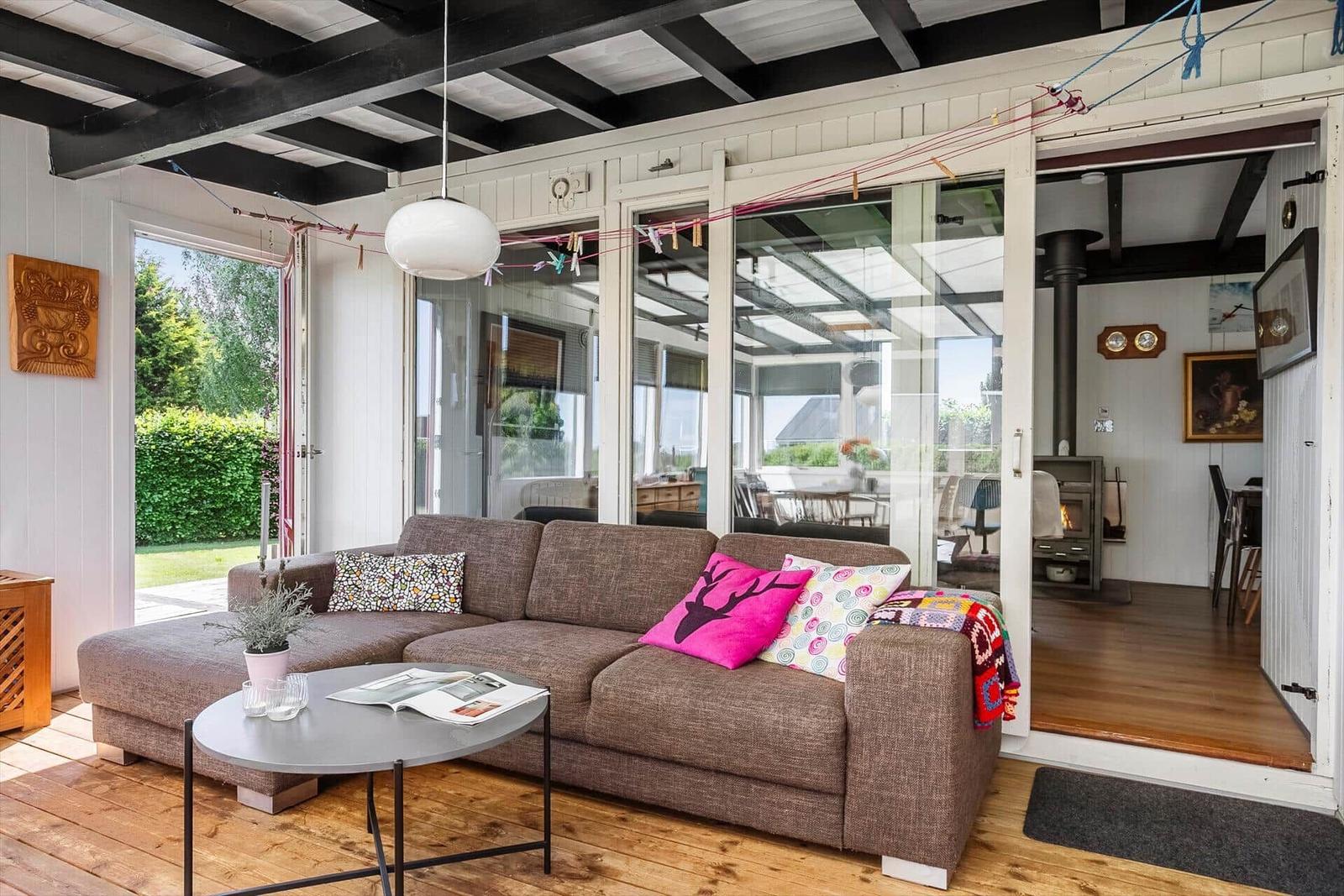 Living room with sofa, table, and view of garden and kitchen.