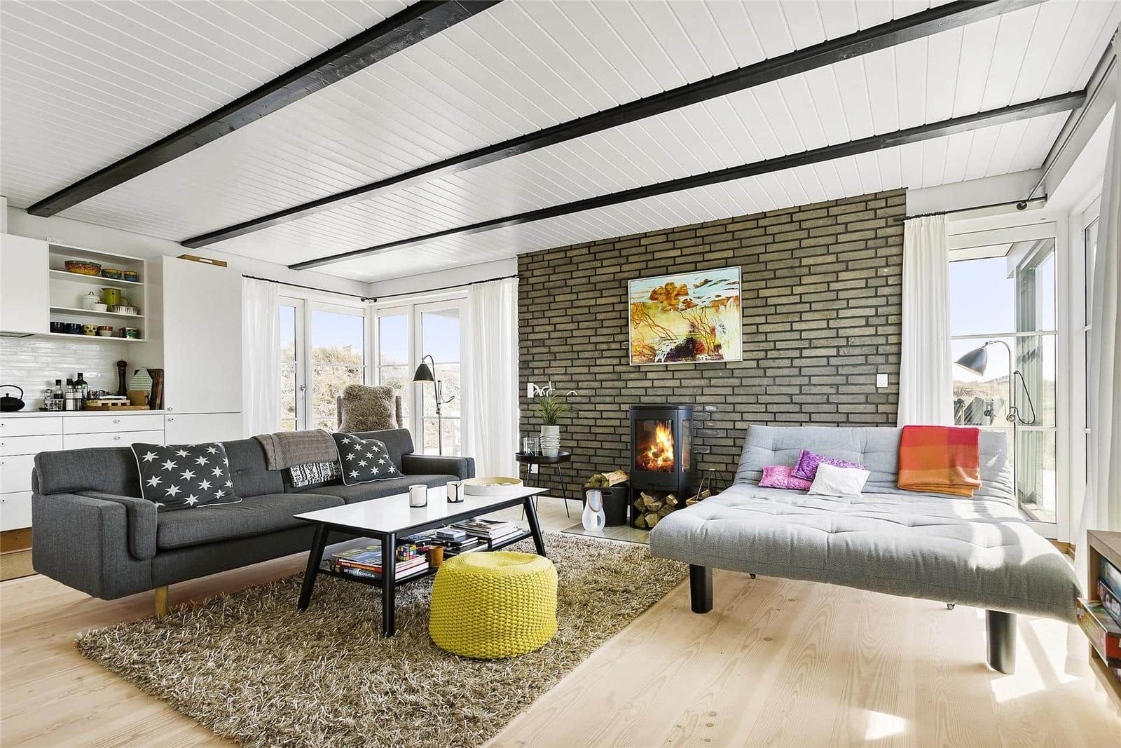 Living room with sofa, futon, fireplace, and large windows.