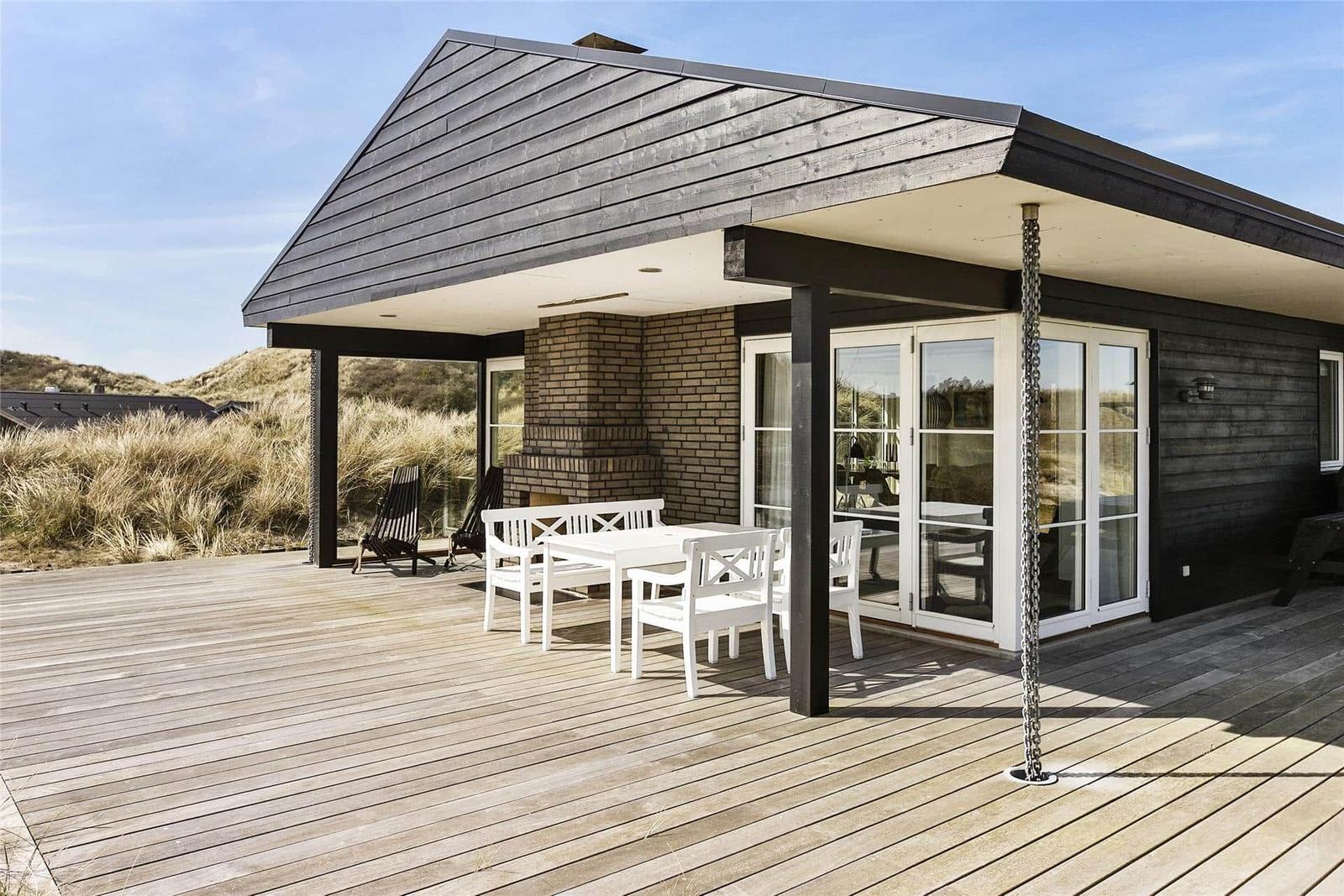 Deck with white table and chairs, wooden flooring, and outdoor grill area.
