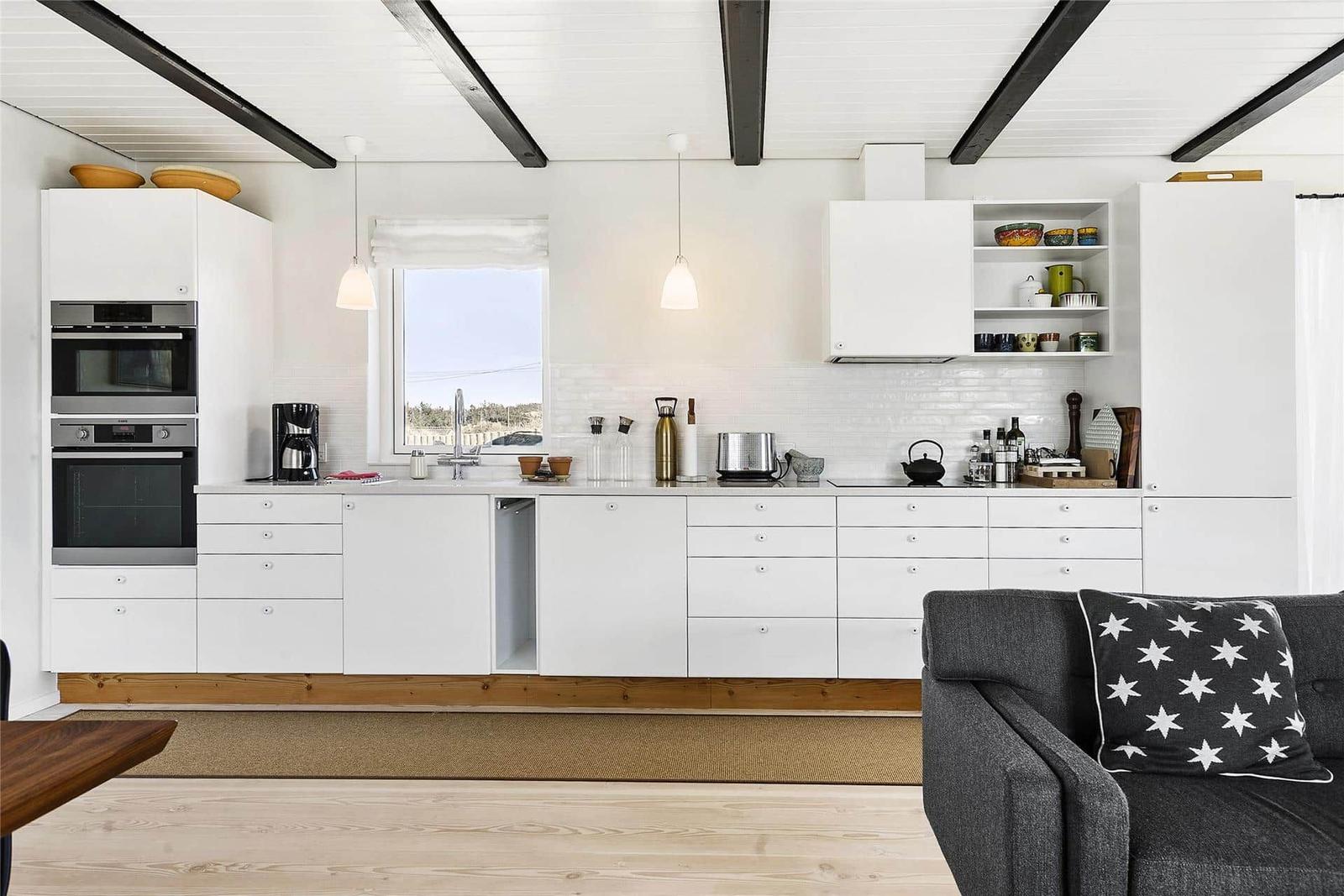 Kitchen with white built-in cabinets, window, and gray sofa with star cushion.