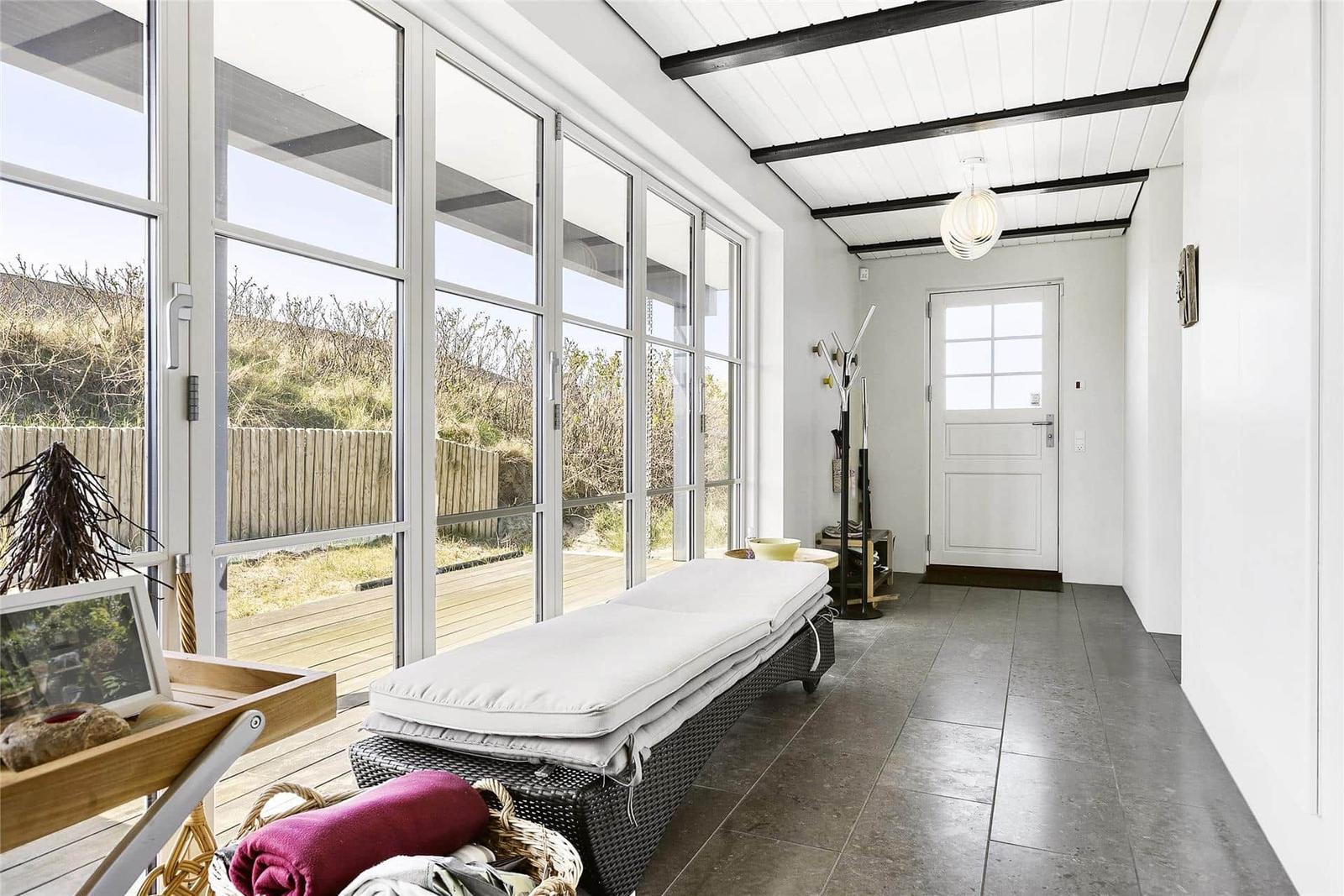 Entrance area with lounge, large windows, and wooden terrace.