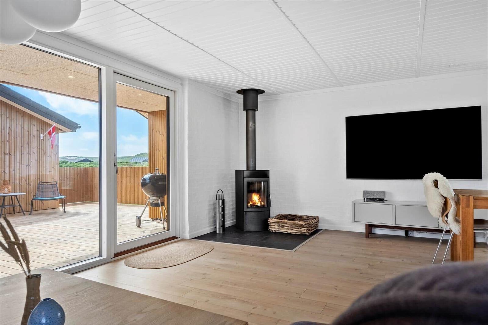 Wohnzimmer mit Kamin, TV und Terrasse mit Grill.